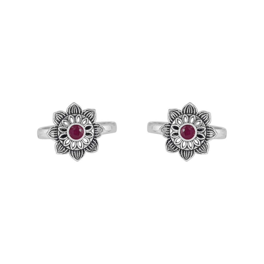Lotus-bloom toe rings with a red center stone in oxidized Pure 92.5 Silver featuring floral detailing and open bands.
