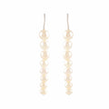 Pearl Descent drop earrings featuring a graduated line of round white pearls with silver hooks for elegant wear.