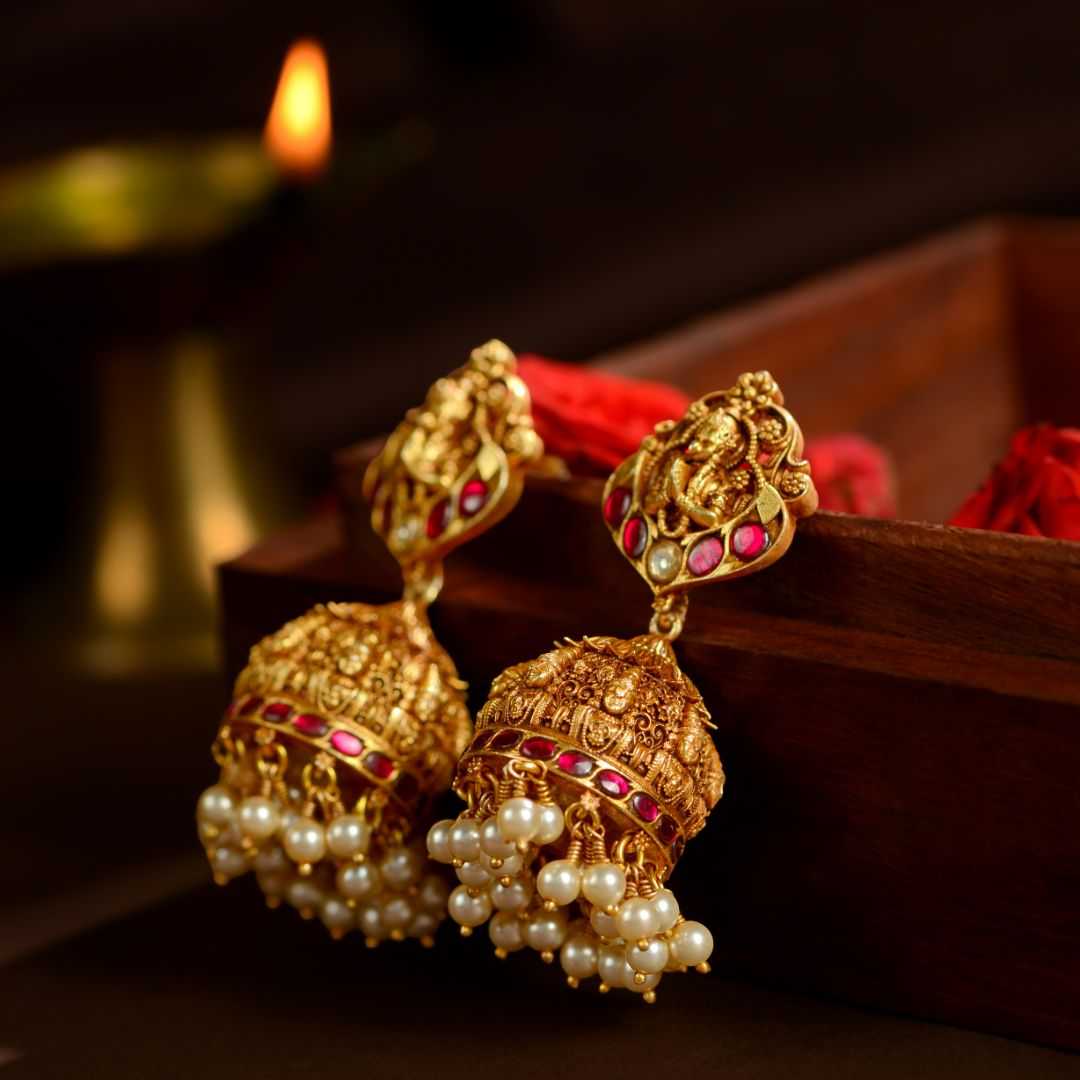 92.5 Silver temple jhumka earrings in gold tone with ruby red stones, Balaji and Garuda motifs, and pearl drop detailing